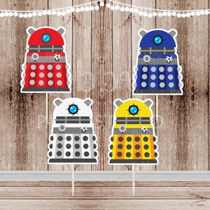 May include: Four different colored Dalek cake toppers. The Daleks are from the Doctor Who television series. The Daleks are red, blue, white, and yellow.