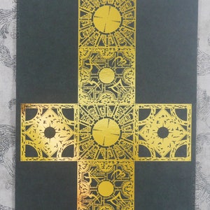 May include: A gold-colored metal puzzle box with intricate designs. The box is made up of four smaller boxes that are connected together. The box is on a black background.