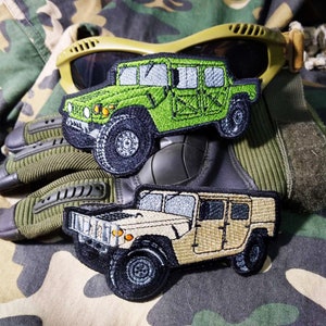 May include: Two embroidered patches of military Humvees. The first patch is green and the second is tan.