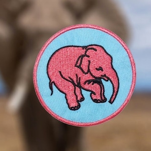 Op de afbeelding: Een ronde blauwe en witte patch met een roze olifant illustratie. De olifant kijkt naar links en heeft zijn slurf opgerold.