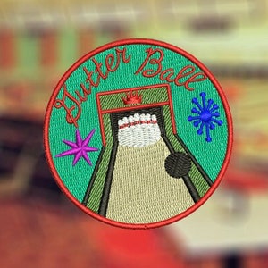 Puede incluir: Un parche redondo bordado de color verde con las palabras "gutter ball" en letras rojas. El parche representa una pista de bolos con una bola de bolos y bolos.