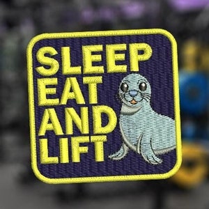 Puede incluir: Un parche bordado amarillo y azul con una foca de dibujos animados y el texto "SLEEP EAT AND LIFT".