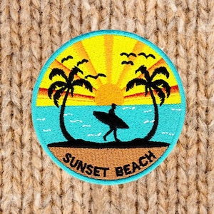 May include: A blue and yellow embroidered patch with a sunset, palm trees, and a surfer. The text "SUNSET BEACH" is written in a white arc below the image.