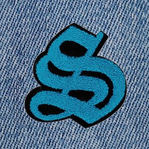 May include: A blue and black embroidered patch shaped like the letter 'S'.