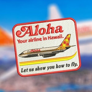 May include: A red, white, and yellow embroidered patch with the text "Aloha Your airline in Hawaii." and a small airplane with the text "Aloha" on it. The text "Let us show you how to fly." is below the airplane.