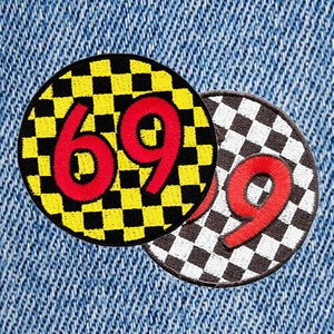 Puede incluir: Dos parches redondos bordados con un patrón a cuadros en blanco y negro. Los parches presentan los números 69 en rojo sobre fondo amarillo y 9 en rojo sobre fondo blanco.