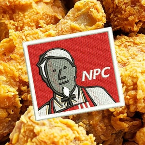 May include: Close-up of golden-brown fried chicken pieces. A red patch with a cartoon image of a man and the letters "NPC" is in the corner. The chicken is crispy and appears freshly cooked.