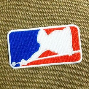 May include: A white embroidered patch with a red, white, and blue baseball logo. The logo depicts a person playing pool with a cue stick and a white ball.