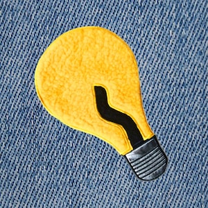 Puede incluir: Una bombilla amarilla con un filamento negro sobre un fondo de mezclilla azul.