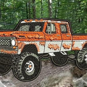 Op de afbeelding: Een geborduurde patch van een vintage Ford pick-up truck met grote banden. De truck is roestig en heeft een witte streep langs de zijkant.