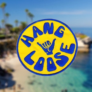 May include: A yellow and blue round patch with the text "HANG LOOSE" in blue lettering and a blue hand gesture in the center.