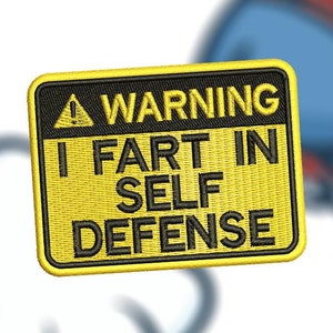 Puede incluir: Parche bordado con fondo amarillo y borde negro. El parche dice "WARNING I FART IN SELF DEFENSE" en texto negro. Una nube de dibujos animados y una figura azul con un sombrero rojo están en el fondo.