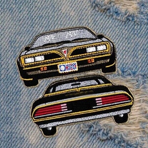 May include: Two embroidered patches of a black Pontiac Trans Am car. The top patch shows the front of the car, while the bottom patch shows the back of the car.