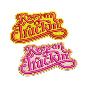 Puede incluir: Dos parches bordados con el texto "Keep on Truckin'" en una fuente retro. El parche superior es amarillo con letras rojas, y el parche inferior es beige con letras rosas.