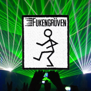 May include: A crowd of people at a concert with green and blue laser lights. A white sign with black text reads "FUKENGRUVEN" and a stick figure dancing.