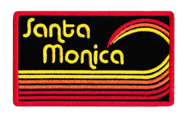 Puede incluir: Parche bordado con la inscripci&oacute;n "Santa Monica" en amarillo, en forma de arco. El parche tiene un fondo negro con rayas amarillas, naranjas y rojas y un borde rojo. El dise&ntilde;o incluye un arco&iacute;ris estilizado.