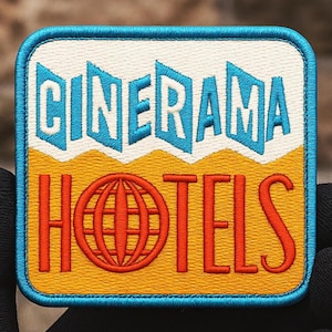 Puede incluir: Parche bordado con las palabras "CINERAMA HOTELS" en turquesa y naranja. El parche tiene un fondo blanco con una sección inferior amarilla y naranja. El parche es cuadrado con esquinas redondeadas y un borde turquesa.