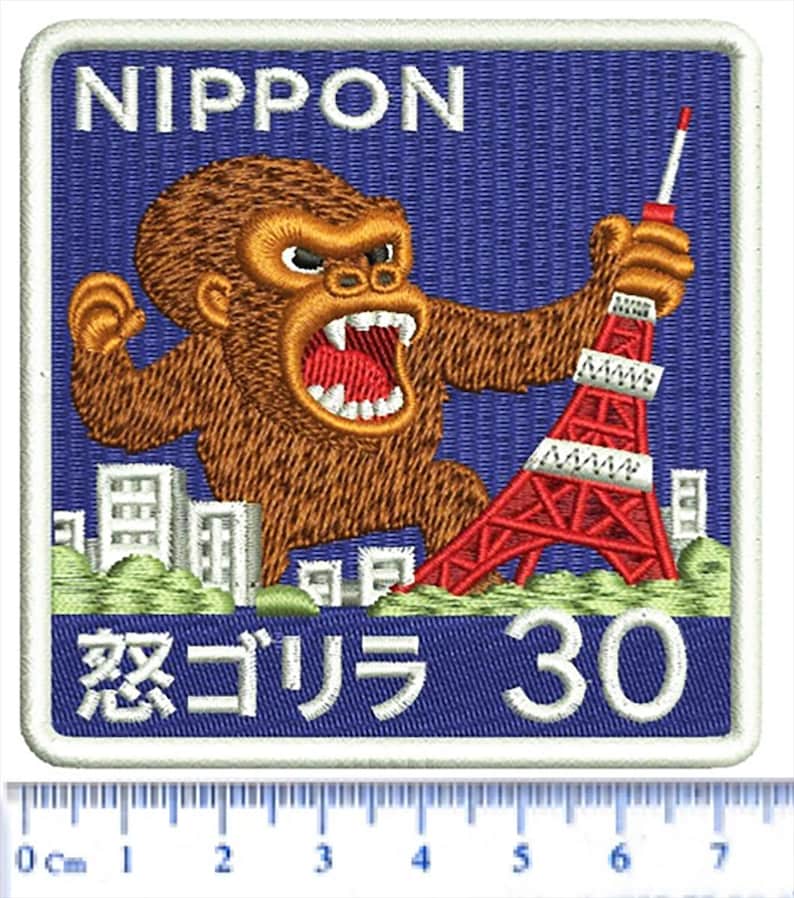 May include: Embroidered patch with a blue background featuring the word "NIPPON" at the top. A brown gorilla is depicted holding a red Tokyo Tower. The Japanese text "怒ゴリラ 30" is at the bottom. The patch is approximately 2.5 inches wide.