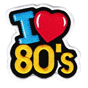 May include: A black and white embroidered patch with a blue "I" and a red heart. The text "80's" is in yellow and outlined in black.