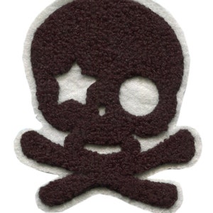 Op de afbeelding: Een bruine vilt schedel en gekruiste beenderen patch met witte contouren. De schedel heeft een ster in een oogkas.