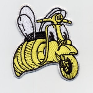 May include: Embroidered patch featuring a yellow scooter with bee wings. The scooter has a yellow body with black accents and a white outline. The wings are white with black details. The patch is on a white background.
