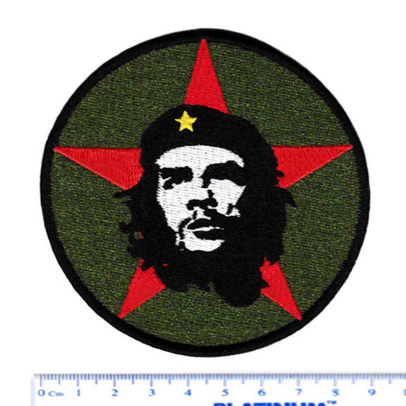 May include: A red star with a green background and a black and white image of Che Guevara in the center. The star has a yellow star in the center.