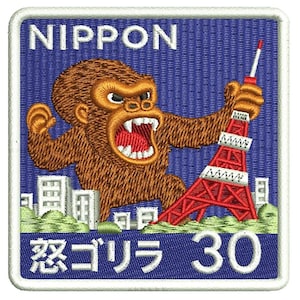 May include: Embroidered patch with a brown gorilla holding a red Tokyo Tower. The patch has the word "NIPPON" at the top and Japanese text and the number "30" at the bottom. The background is blue.