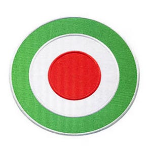 May include: A round, embroidered patch with a green outer ring, a white middle ring, and a red center circle.