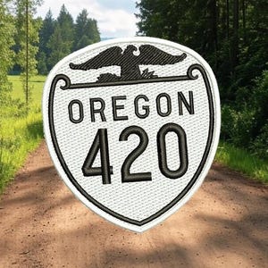 May include: White and black embroidered patch with the text "OREGON 420" inside a shield shape with an eagle design above the text.