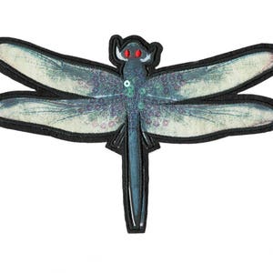 May include: A blue and white dragonfly with red eyes, embroidered on a black fabric patch.