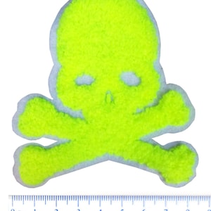 May include: A bright yellow skull and crossbones patch made of fuzzy fabric. The patch is approximately 8 cm wide.