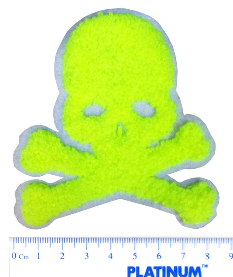 May include: A bright yellow skull and crossbones patch made of fuzzy fabric. The patch is approximately 8 cm wide.