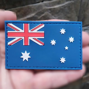May include: A blue and red Australian flag patch with white stars. The patch is made of a rubber-like material and has a stitched border.
