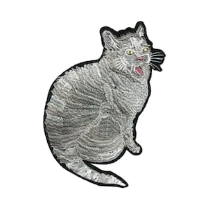 May include: A gray and white embroidered cat patch with a black outline. The cat has an open mouth and is sitting on its hind legs.