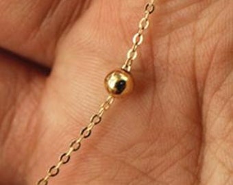 May include: A delicate gold chain necklace with a single small gold bead.