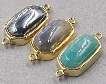 May include: Three gold-toned connector charms with different gemstone inlays. The charms feature a rectangular shape with rounded edges. The gemstones are a dark grey, a light grey, and a light green.
