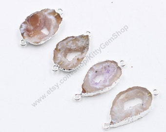 May include: Four agate gemstone pendants with silver-toned metal loops. The agate is translucent and has a white, pink, and purple color. The pendants are oval-shaped and have a natural, irregular edge.