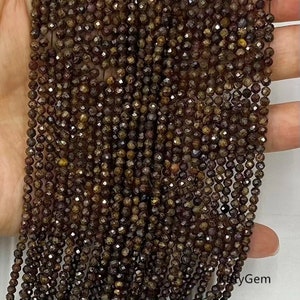 Op de afbeelding: Een streng bruine facetgeslepen edelsteen kralen. De kralen zijn klein en hebben een glanzende, metallic afwerking.
