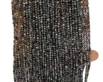 May include: A strand of gray faceted gemstone beads. The beads are small and round, and they are strung on a thin wire. The beads are all the same size and shape, and they are arranged in a uniform pattern.