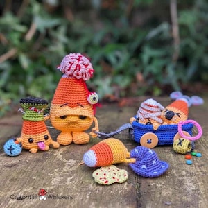 May include: A set of five crocheted candy corn characters. One candy corn is wearing a green hat and has a tongue sticking out. Another candy corn has a brain on top of its head and a googly eye. The other three candy corns are in a blue wagon with a button on the front. The candy corns are on a wooden surface with a green background.