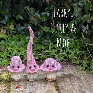 Op de afbeelding: Drie gehaakte paddenstoelfiguren met roze hoeden met witte stippen en beige stelen. De middelste figuur heeft een hoge, puntige hoed. De tekst "Larry, Curly & Moe" staat boven de figuren en "Cottontail Whiskers" staat onderaan.