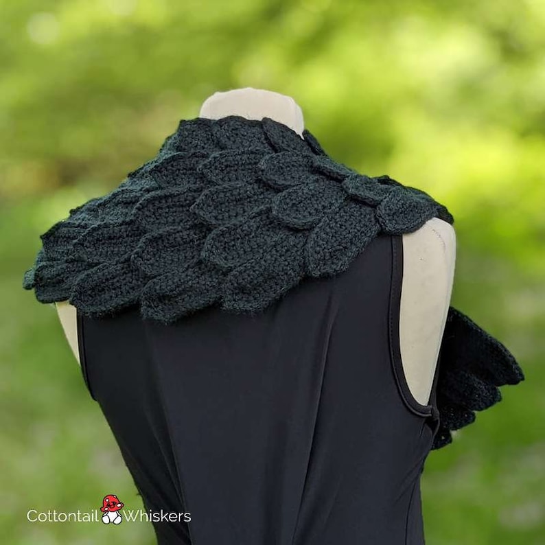 May include: A dark green crocheted leaf-shaped collar, worn on a black sleeveless top. The collar is made of individual crocheted leaves that are joined together to form a continuous piece.
