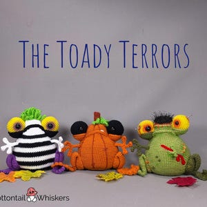 May include: Three crocheted toad plushies, each with unique features. One is black and white striped, one is orange and shaped like a pumpkin, and one is green with a red paintbrush. The title "The Toady Terrors" is above the plushies.