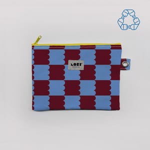 May include: A rectangular zippered pouch with a repeating pattern of blue and burgundy scalloped shapes. The zipper is yellow, and the pouch has a small silver grommet. The brand name "LORI BARCELONA" is on a small tag.