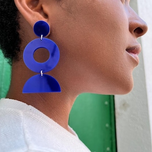 May include: A pair of blue geometric earrings with a large circle, a smaller circle, and a half-circle shape.