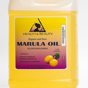 May include: A yellow plastic jug of Marula Oil, a natural beauty product. The label reads "Health & Beauty", "Organic and Pure", "Marula Oil", "Sclerocarya Birrea", "7 LB. 3178 ml.", "All Natural", "Extraction Method: Cold Pressed Refined", "Obtained from KERNELS", "Country Of Origin Namibia", and "Exp. date". The jug is sitting on a white surface.