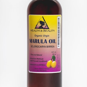 May include: A brown glass bottle of organic virgin marula oil, labeled "HEALTH & BEAUTY" with a yellow triangle and a woman's silhouette. The bottle contains 12 fluid ounces (355 ml) and is labeled "Pure and Natural" with the extraction method, "Cold Pressed Unrefined". The label also states that the oil is obtained from kernels and the country of origin is Namibia.