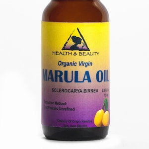 May include: A brown glass bottle of Marula Oil with a black cap. The label is yellow and purple with the text "HEALTH & BEAUTY Organic Virgin MARULA OIL". The bottle contains 0.5 fl oz (15 ml) of oil. The image also includes a "FREE SHIPPING" banner.