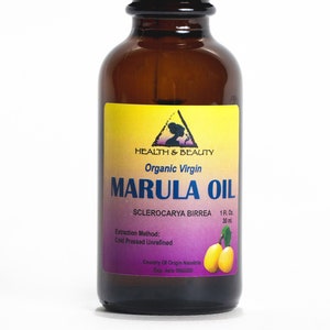 May include: A brown glass bottle with a black dropper top, labeled "Organic Virgin Marula Oil" with the text "Sclerocarya Birrea 1 Fl. Oz. 30 ml" and "Extraction Method: Cold Pressed Unrefined" and "Country Of Origin Namibia".