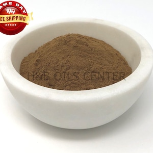 May include: A white ceramic bowl filled with a brown powder. The powder is a natural herb or spice.